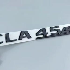 May include: Black CLA 45 S emblem on a white backing. The emblem features the text "CLA 45 S" in a bold, sans-serif font. The letters are glossy and appear to be made of a durable material.