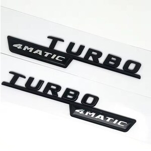 May include: Two black car emblems with the text "TURBO 4MATIC" in a white font. The emblems are on a white background and appear to be made of a glossy material.