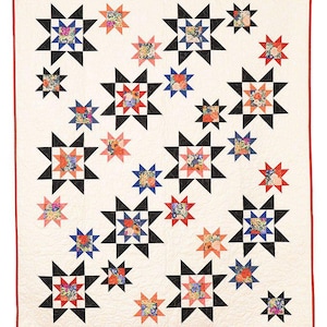 Könnte beinhalten: Eine weiße Steppdecke mit rotem Rand zeigt ein sich wiederholendes Muster aus schwarzen und weißen Sternen mit buntem Blumenstoff in der Mitte jedes Sterns.