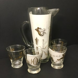 May include: A set of five vintage glass drinkware pieces with a gold mermaid and sea life design. The set includes a pitcher and four glasses.