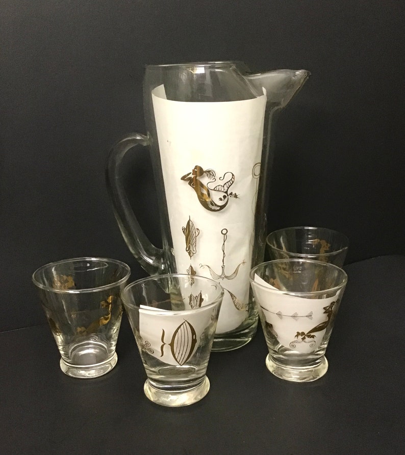 May include: A set of five vintage glass drinkware pieces with a gold mermaid and sea life design. The set includes a pitcher and four glasses.