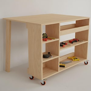 May include: A light-colored wooden workbench with integrated shelving and a fold-down table section. The workbench has red-wheeled casters and is stocked with tools, including a tape measure, screwdrivers, and a drill.