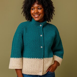 Puede incluir: Chaqueta de crochet color turquesa y crema con cuello alto y tres botones. La chaqueta presenta un patrón de puntadas texturizadas y mangas tres cuartos. La parte inferior y los puños son de color crema, creando un diseño bicolor.