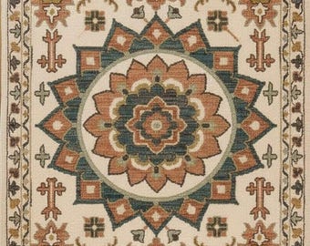 May include: Cream-coloured rectangular rug with an elaborate pattern. The design includes a central floral medallion in teal, rust, and cream, surrounded by geometric and floral motifs in similar tones. The rug has a fringed border.