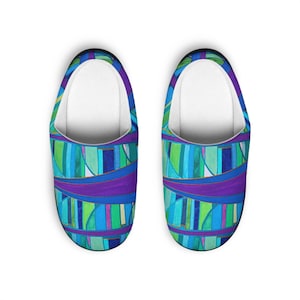 May include: A pair of colorful slippers with a vibrant abstract design. The pattern features vertical stripes in shades of blue, green, and purple, with a white interior. The slippers are designed for indoor use.
