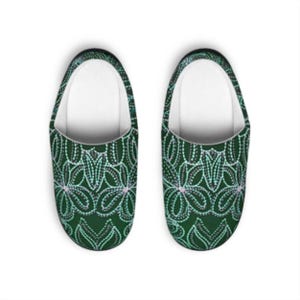 May include: A pair of green slippers with a floral pattern made of white and light blue dots. The interior is white. The slippers are designed for indoor use and are a comfortable footwear option.