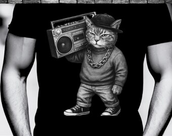 May include: Black t-shirt featuring a cat wearing a backwards cap, gold chain, and holding a boombox. The cat is dressed in a gray sweater and jeans, with black and white sneakers. The image is a black and white illustration.