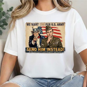 May include: White t-shirt featuring a vintage-style U.S. Army recruitment poster. The graphic includes Uncle Sam pointing, a soldier, and the text "WE WANT YOU FOR U.S. ARMY" and "SEND HIM INSTEAD!"
