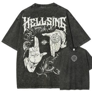 May include: A charcoal gray acid-wash t-shirt featuring a large white graphic on the back with the text HELLSING, a central eye, and two hands forming a frame. The front of the shirt displays a small circular emblem with a pentagram design.
