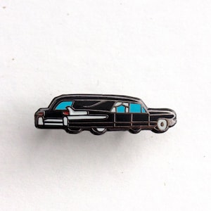 Puede incluir: Pin de esmalte negro de un coche fúnebre negro vintage con ventanas tintadas de azul.