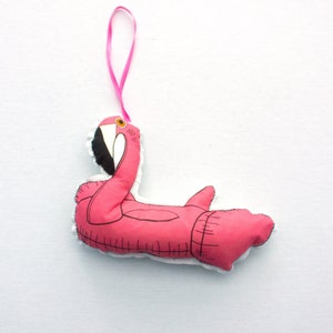 May include: Pink flamingo-shaped inflatable pool float ornament with a pink ribbon for hanging.