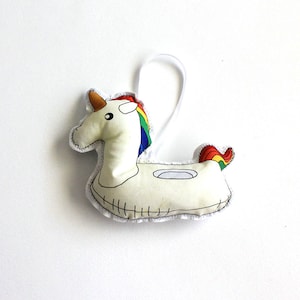 May include: White fabric unicorn pool float ornament with a rainbow mane and tail.