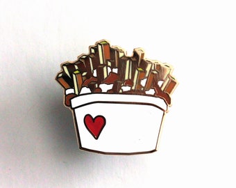 Pode incluir: Pin de esmalte dourado com um recipiente branco com um coração vermelho e um monte de batatas fritas marrons dentro.