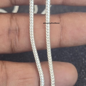 Könnte beinhalten: Nahaufnahme von zwei silberfarbenen Schlangenkettchen. Die Ketten haben ein strukturiertes, schuppenartiges Muster. Der Text "JewelryCmStore" ist auf dem Bild zu sehen. Die Ketten werden vor einem neutralen Hintergrund präsentiert.