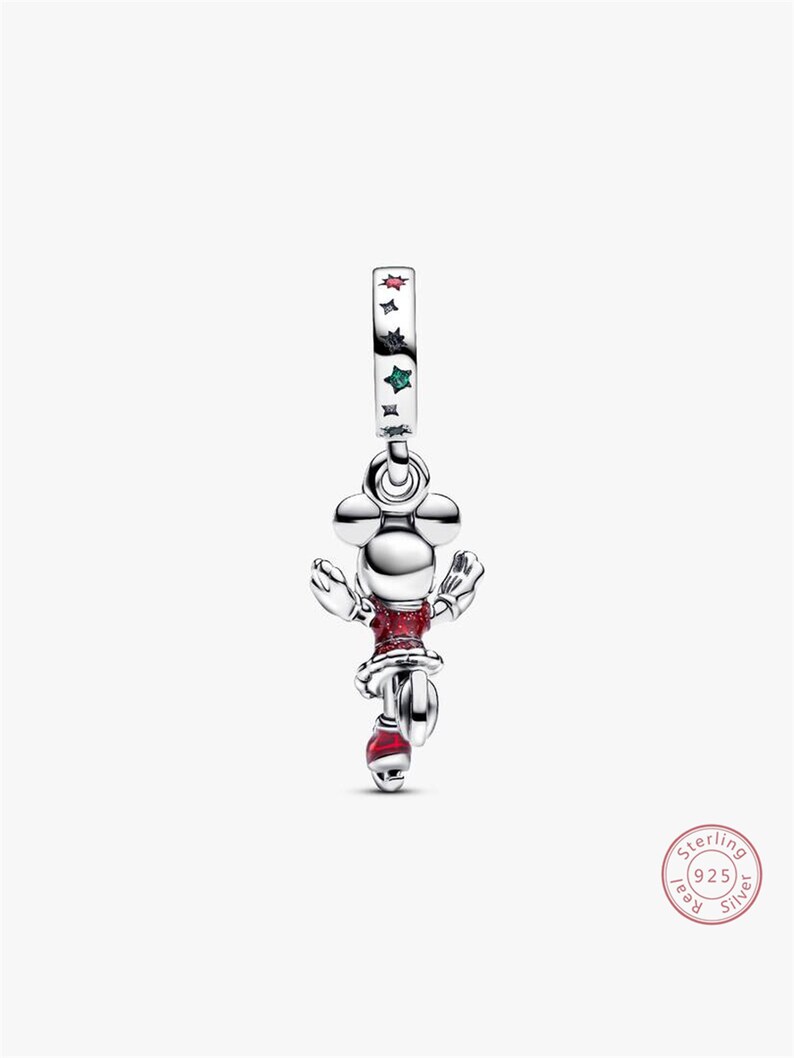 Może przedstawiać: Srebrny charms przedstawiający Minnie Mouse. Charms ma czerwoną sukienkę i buty, z opaską ozdobioną gwiazdami. Ten element biżuterii jest w stylu Disneya, idealny do bransoletki lub naszyjnika.