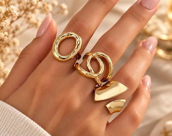 Conjunto de anillos llamativos en tono dorado: anillos modernos ovalados y esculturales. Joyería femenina audaz.