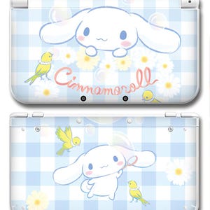 Può includere: Custodia bianca e blu per Nintendo 3DS con un personaggio di coniglietto dei cartoni animati, margherite e uccelli gialli su un motivo a quadretti blu. La parola "Cinnamoroll" è scritta in rosa. La custodia è bianca e ha un design a cerniera.