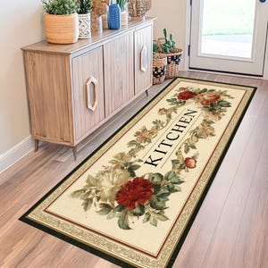 May include: A rectangular kitchen rug with a cream background, framed by a black border and a decorative floral pattern. The rug features a central floral design with the word "KITCHEN" in black letters.