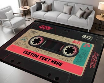 Könnte beinhalten: Rechteckiger Teppich mit einem Retro-Kassetten-Design. Der Teppich hat einen schwarzen Hintergrund mit einem roten und türkisfarbenen Etikett. Der Text "CUSTOM TEXT HERE" ist zu sehen. Der Teppich befindet sich in einem Wohnzimmer.