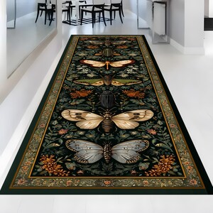 May include: A rectangular, dark green rug with a detailed insect and floral pattern. The rug features various insects, including butterflies and beetles, in shades of cream, brown, and green, set against a dark green background with floral accents. The border is a lighter green with a floral design.