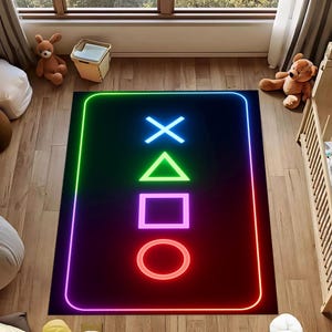Könnte beinhalten: Schwarzer rechteckiger Teppich mit Neon-PlayStation-Controller-Symbolen: X, Dreieck, Quadrat und Kreis. Die Symbole sind blau, grün, pink und rot. Der Teppich hat einen Neonrand und liegt auf einem Holzboden.