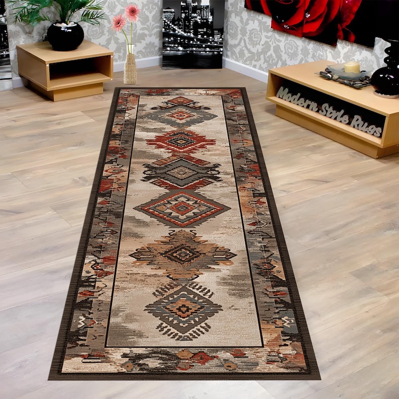 May include: A rectangular runner rug with an intricate geometric pattern in shades of brown, red, and gray. The rug features a central design of diamond and rectangular shapes, bordered by a darker brown trim. The rug is designed for a hallway or entryway.