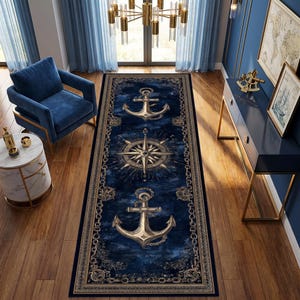 May include: A rectangular runner rug featuring a deep blue background with a central gold compass rose flanked by two large gold anchors. The border is decorated with a repeating gold chain pattern and intricate nautical motifs on a tan frame.