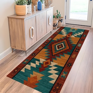 Pode incluir: Um tapete retangular em estilo Southwestern com um padrão geométrico em azul-petróleo, laranja, ferrugem e creme. O tapete está colocado sobre um chão de madeira clara, com um armário de madeira e uma porta ao fundo.