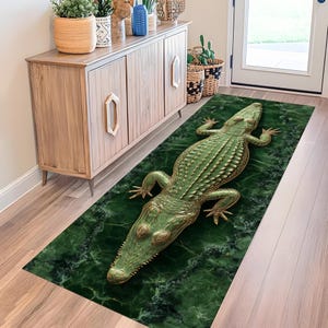Könnte beinhalten: Rechteckiger Teppich mit einem grünen und goldenen Alligator-Design auf einem marmorierten grünen Hintergrund. Der Teppich liegt auf einem Holzboden. Der Alligator hat detaillierte Schuppen und ein realistisches Aussehen. Ein dekoratives Element für den Eingangsbereich.
