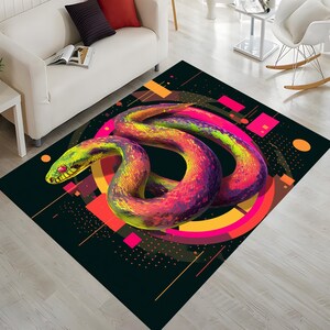 Peut inclure: Tapis rectangulaire avec un motif de serpent stylisé et vibrant. Le serpent, aux tons de jaune, vert, rose et violet, est enroulé sur un fond noir avec des formes géométriques orange et rose. Le tapis est posé sur un sol en bois clair.