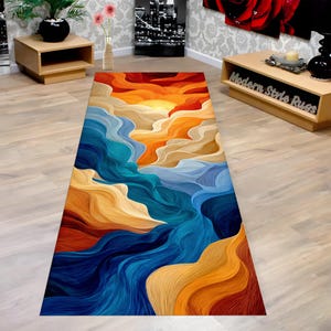 May include: A rectangular rug with an abstract design featuring flowing lines in shades of blue, orange, and tan, resembling a sunset over water. The rug's design is a vibrant and artistic addition to any room.