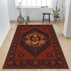 Può includere: Un tappeto rettangolare con un motivo geometrico rosso e blu navy. Il tappeto presenta un ritratto centrale di un uomo con occhiali da sole. Il tappeto è posato su un pavimento in legno chiaro.