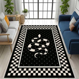 May include: Black and white area rug with a snake design. The rug features a black field with a white snake illustration and small white dots. A checkered border frames the central design, adding a graphic element to the floor covering.