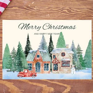 Puede incluir: Tarjeta de Navidad con una ilustración en acuarela de una escena de pueblo nevado. La tarjeta presenta dos casas, árboles de hoja perenne, una camioneta roja y un muñeco de nieve. El texto dice "¡Feliz Navidad y Próspero Año Nuevo!"