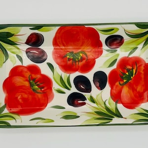 Può includere: Piatto da portata rettangolare in ceramica con un design dipinto a mano con tre grandi pomodori rossi, olive nere e foglie verdi su sfondo crema. Il piatto ha un bordo verde.