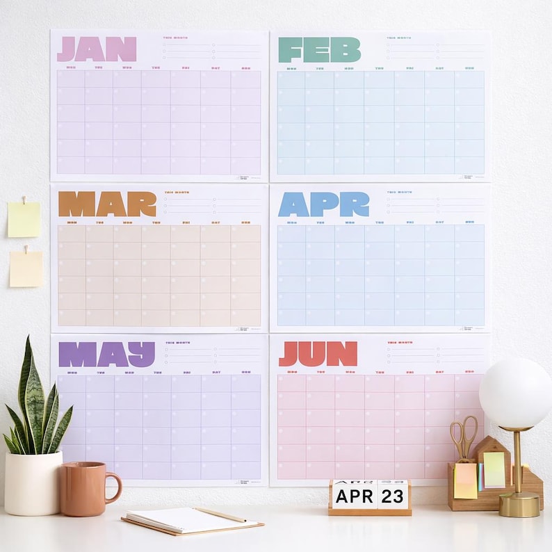 May include: Six colorful monthly wall calendars, each with a different pastel background and the month's name in bold letters. The months are January, February, March, April, May, and June. A wooden block calendar displays "APR 23".