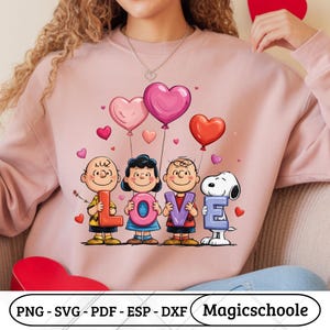 Peut inclure: Sweat-shirt rose avec un motif des personnages de Peanuts épelant "LOVE" avec des ballons en forme de cœur. Le motif comprend Charlie Brown, Lucy, Linus et Snoopy. Le sweat-shirt a un col rond.