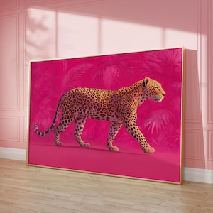 May include: A framed art print featuring a leopard walking across a vibrant pink background. The leopard has a spotted coat and is set against a backdrop of stylized pink foliage. The artwork is displayed in a room with pink walls and a wooden floor.