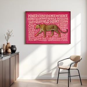 May include: A framed artwork featuring a leopard illustration in shades of brown and black against a vibrant pink background. The artwork includes text such as "Power," "Confidence," and "Wild." The piece is displayed in a modern interior setting.