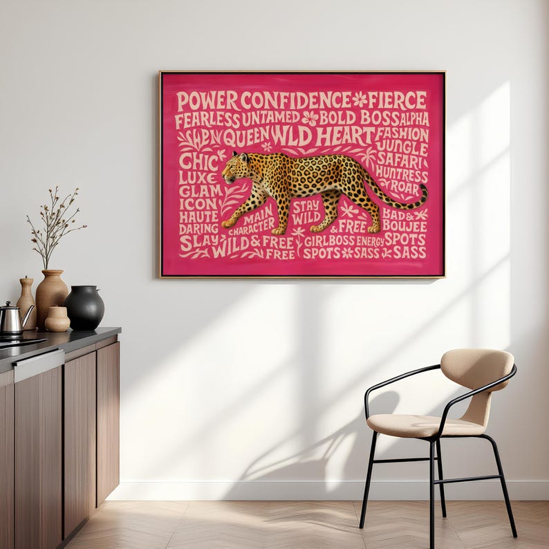 May include: A framed artwork featuring a leopard illustration in shades of brown and black against a vibrant pink background. The artwork includes text such as "Power," "Confidence," and "Wild." The piece is displayed in a modern interior setting.