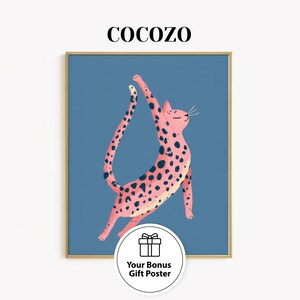 May include: A framed art print featuring a pink cat with black spots, stretching upwards against a blue background. The word "COCOZO" is at the top. A bonus gift poster is included.
