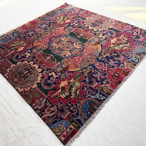 May include: A square area rug featuring a complex, multi-colored pattern with deep blue, red, green, and gold tones. The design includes intricate floral motifs, stylized animal figures, and geometric borders, finished with short fringe on two sides.