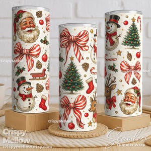 Puede incluir: Tres vasos con temática navideña con diseños festivos. Cada vaso presenta un fondo crema con ilustraciones de Papá Noel, muñecos de nieve, árboles de Navidad, lazos y bastones de caramelo. Los vasos son cilíndricos y se apoyan en bloques de madera y una estera tejida.