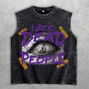 Könnte beinhalten: Ein ärmelloses, dunkelgraues T-Shirt mit Used-Look. Das Shirt zeigt den Text "I SEE DEAD PEOPLE" in Lila, mit einer Augengrafik in der Mitte. Goldfarbene Klebeband-Akzente sind um den Text platziert.