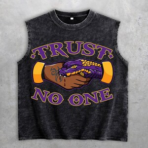 Könnte beinhalten: Schwarzes ärmelloses Shirt mit dem Text "TRUST NO ONE" in Lila. Die Grafik zeigt einen lila und gelben Schlangenkopf, der einer Person die Hand schüttelt, mit einem Tattoo auf dem Arm. Das Shirt ist ärmellos.