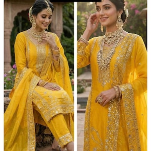 May include: A woman wearing a bright yellow salwar kameez suit with gold embroidery and jewelry. The suit includes a long-sleeved tunic, matching pants, and a dupatta. The text "RiddhiSiddhiTextile" is visible in the image.