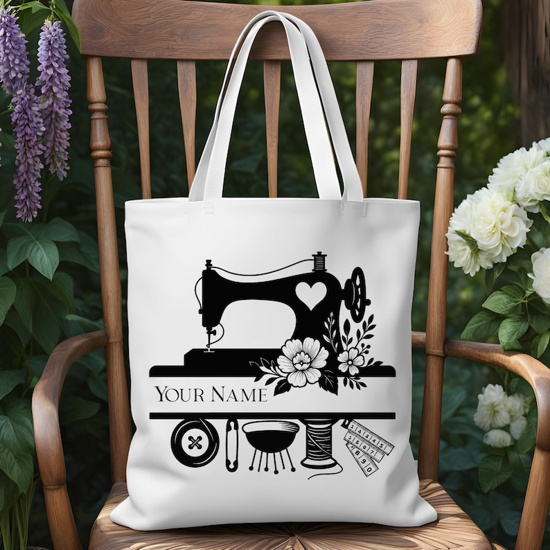 Pode incluir: Bolsa tote branca com uma silhueta preta de uma m&aacute;quina de costura com um cora&ccedil;&atilde;o, flores e o texto "YOUR NAME". Abaixo est&atilde;o no&ccedil;&otilde;es de costura como um bot&atilde;o, alfinete, linha e fita m&eacute;trica. A bolsa tem duas al&ccedil;as brancas.