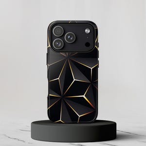Könnte beinhalten: Schwarze Handyhülle mit geometrischem Design und goldenen Akzenten. Die Hülle hat eine glänzende Oberfläche und ein erhöhtes Kameramodul. Das Design ist ein sich wiederholendes Muster geometrischer Formen. Die Handyhülle wird auf einem schwarzen Ständer präsentiert.