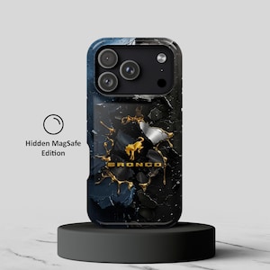 Puede incluir: Una funda de teléfono negra y azul oscuro con un logotipo de caballo Bronco dorado y el texto BRONCO en oro. El diseño incluye un efecto texturizado agrietado con acentos líquidos dorados. El texto Hidden MagSafe Edition aparece a la izquierda.