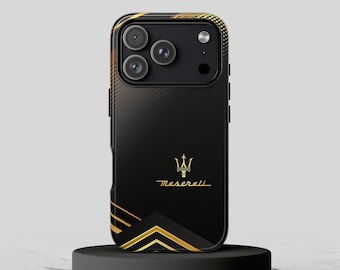 Puede incluir: Una funda de smartphone negra con el logotipo del tridente de Maserati y el texto en dorado. El diseño incluye líneas geométricas doradas en la parte inferior y un patrón de puntos degradados en oro en la parte superior, rodeando la cámara.